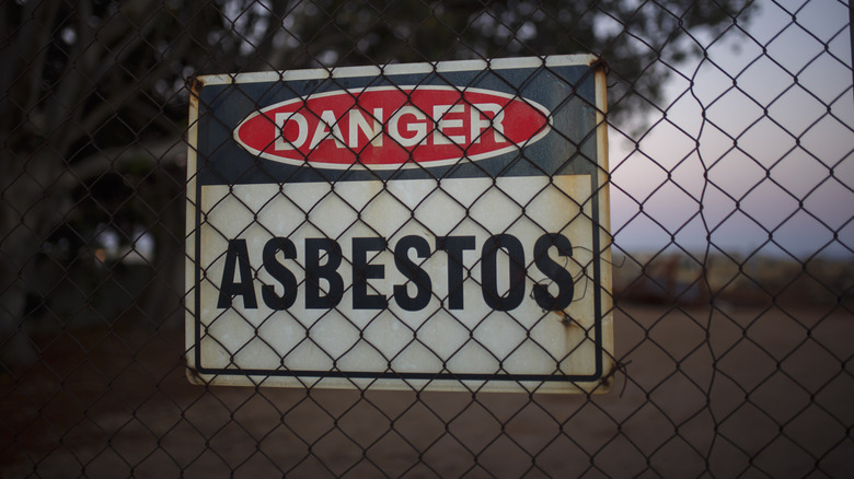 Abestos danger sign behind a metal fence
