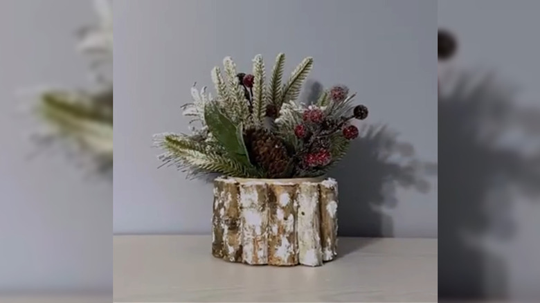 Container surrounded by wood pieces and filled with holiday florals