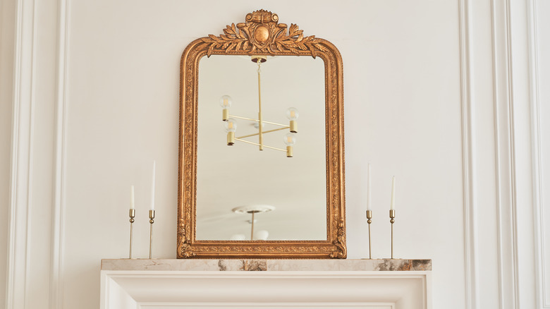 A mirror in a classic frame on mantel with candlesticks