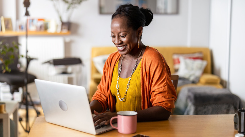 Smiling woman on her laptop at home