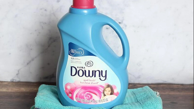 Large tub of Downy fabric softener on folded towels on wood table