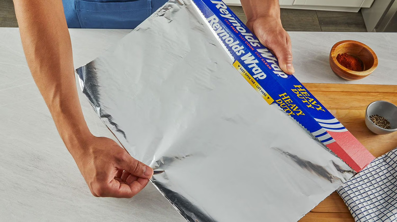 Man unrolling heavy duty Reynolds Wrap from box