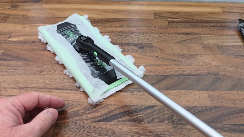 Swiffer broom with heavy duty dry pad on bottom on wood floor