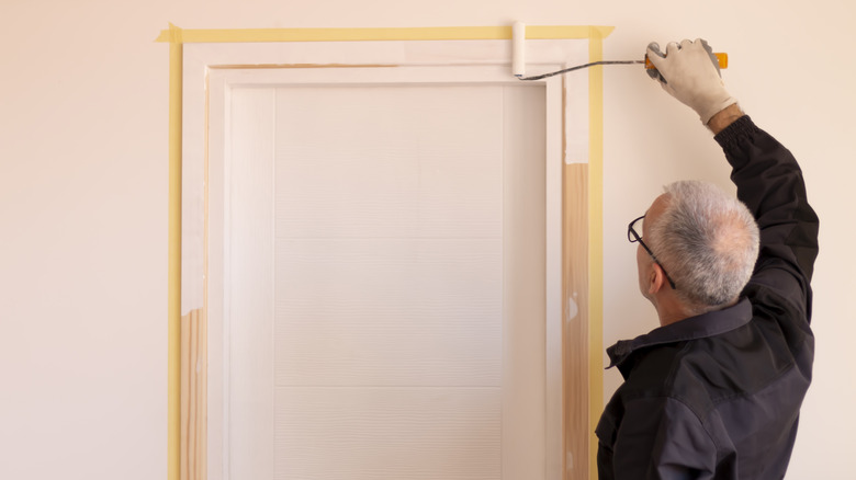 man painting door and door frame in house