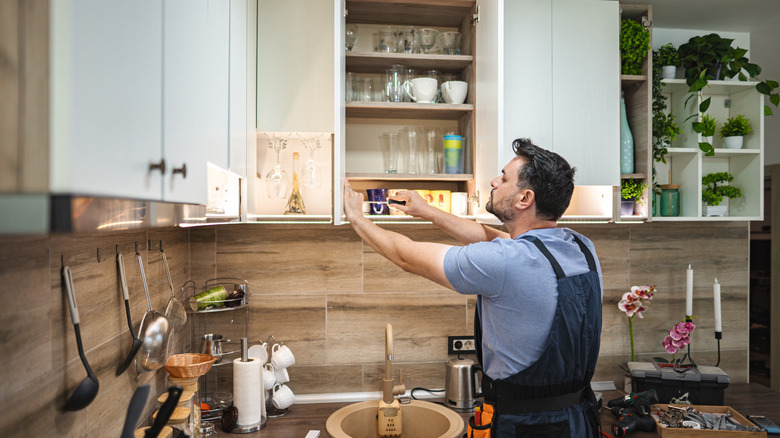 Handyman installing led strip lights under kitchen cabinets