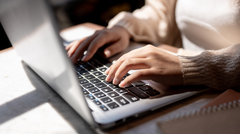 Close-up of a pair of hands on a laptop keyboard doing research