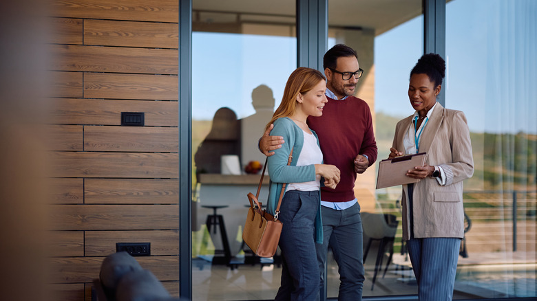 A young couple goes through house plans with a real estate agent outside a prospective home
