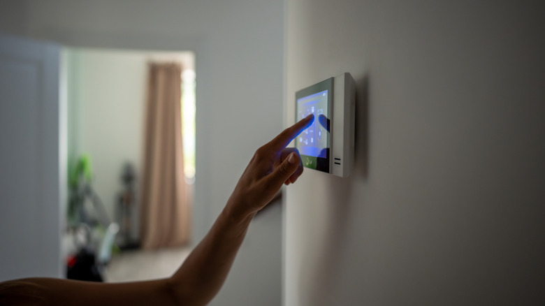 Close-up shot of a hand using a smart home control panel that's mounted on a wall