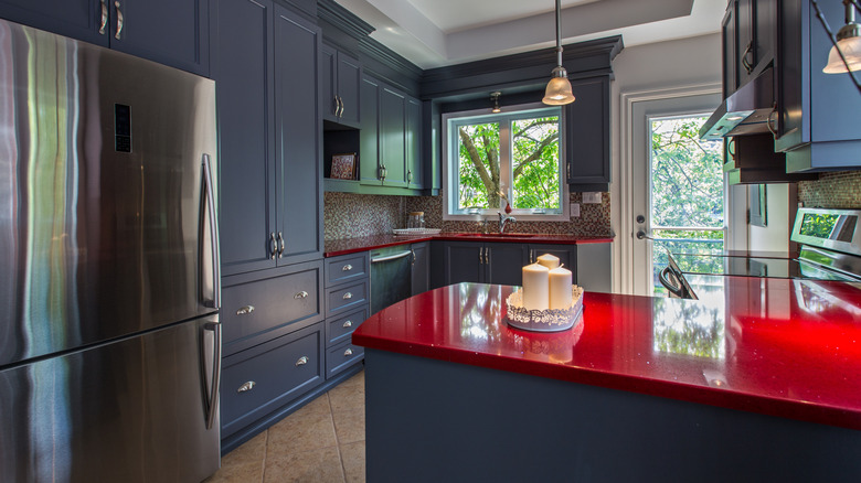 Dark kitchen with deep blue cabinets and red counters