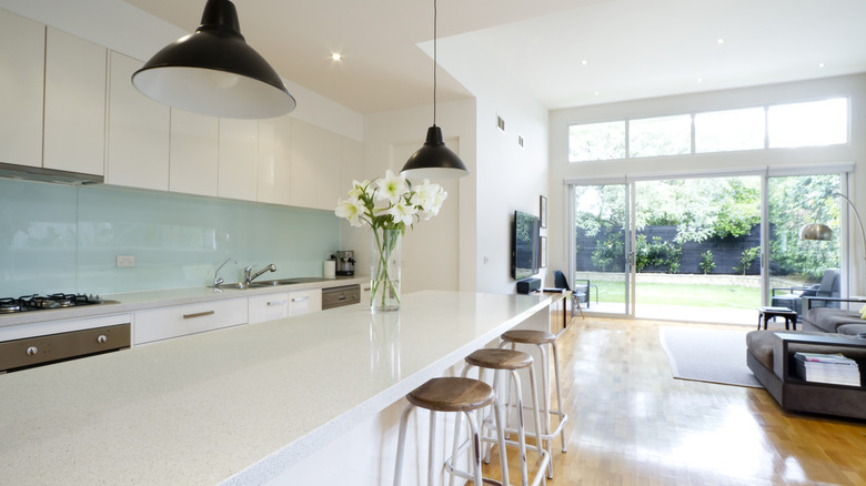 Open concept kitchen with white counters and pastel blue backsplash