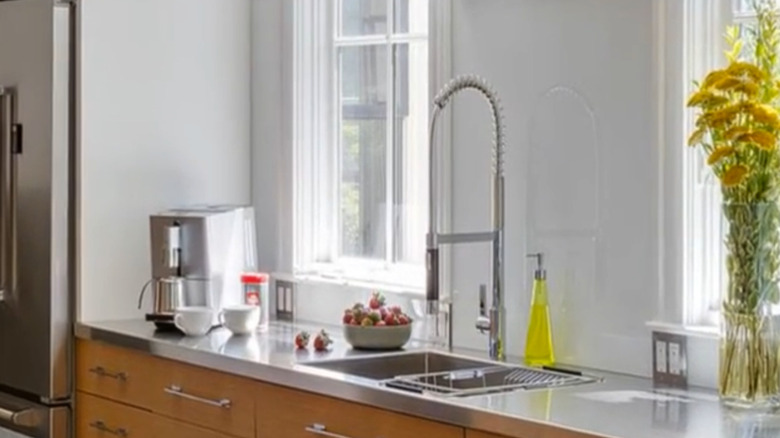 Stainless steel counter in a modern kitchen with white walls and natural light