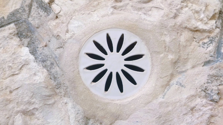 A flower petal-shaped shower drain on stone floor