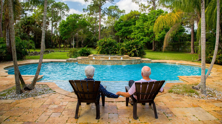 Senior couple sitting beside pool