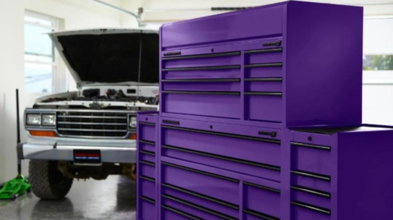 A large purple tool and hardware storage cabinet by U.S. General in front of a truck parked in a garage with the hood opened