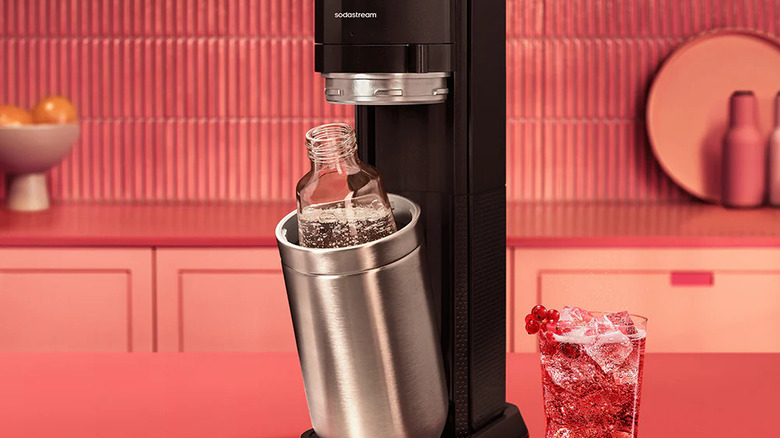 SodaStream Duo with a fizzy drink on the counter next to the machine and pink cabinets in the background