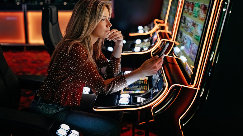 Woman sitting in front of a slot machine in a dim lit room
