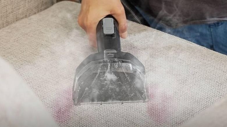 Woman using a steam cleaner to remove stains from her couch