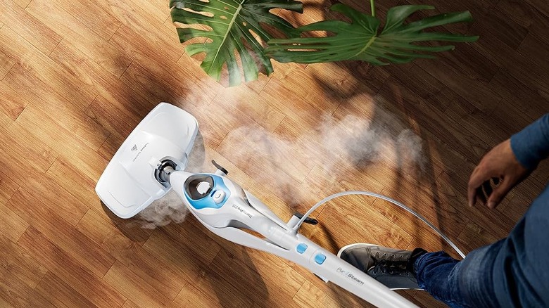 Man using a white and blue steam cleaner on floors