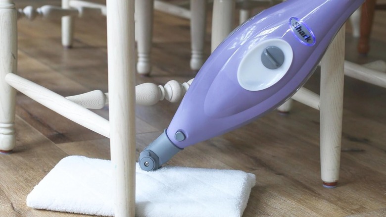 A steam pocket mop being used to clean under a chair