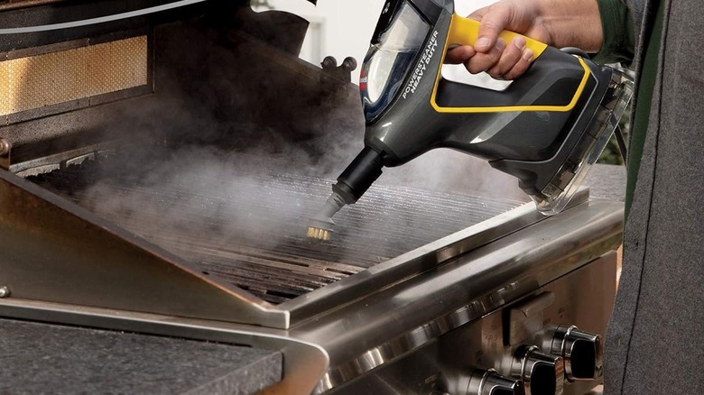 Man using a steam cleaner on a dirty grill