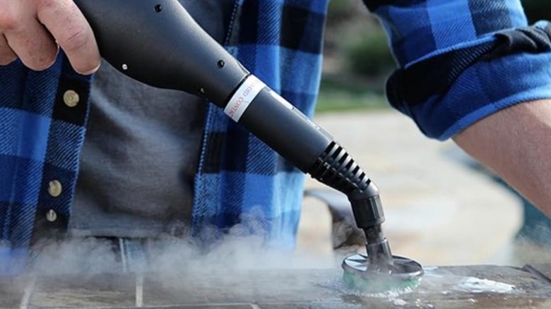 Man using a steam cleaner on a brick surface