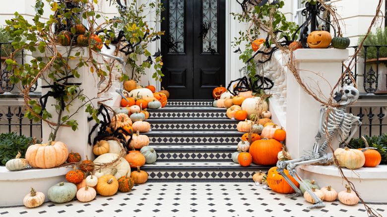 A series of pumpkins and other Halloween decorations leading up the stars to a home's front door