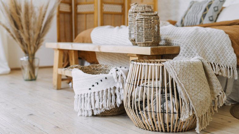 Two backets and a wicker lantern on a bench in front of a bed