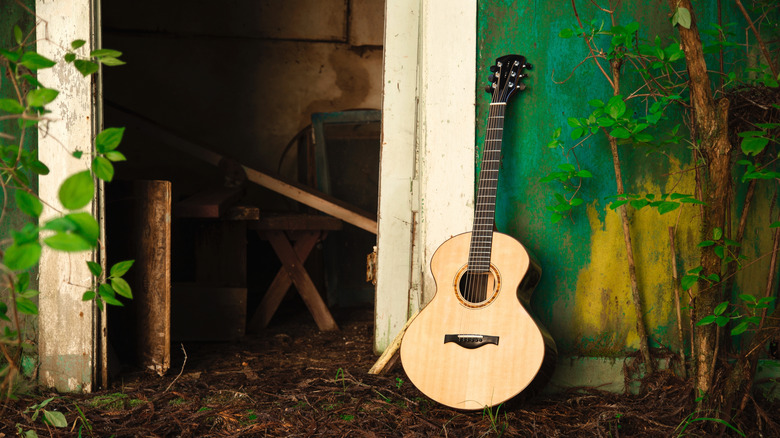 A wooden guitar placed against a shed