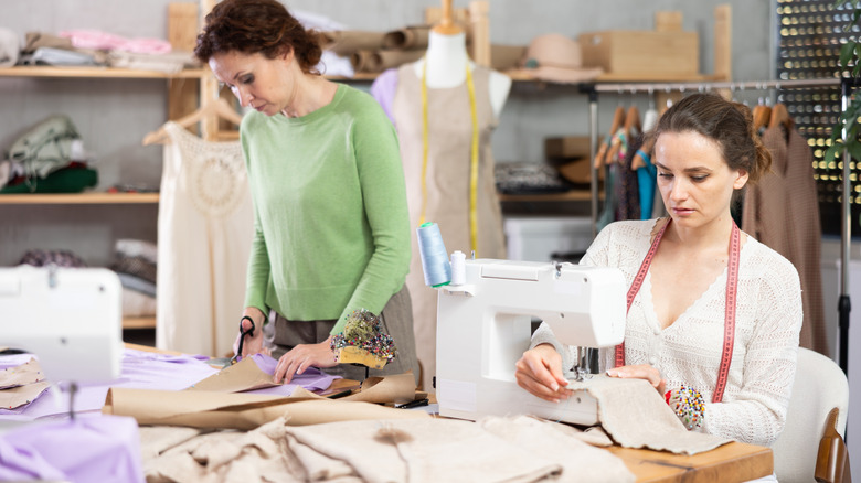Two women using a sewing machine and scissors