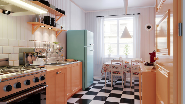 mid-century kitchen with bright pink counters and teal fridge