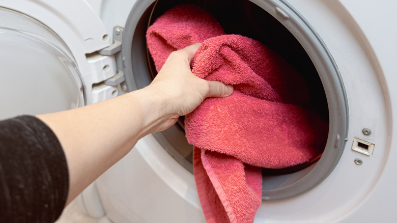 hand putting towel in washer