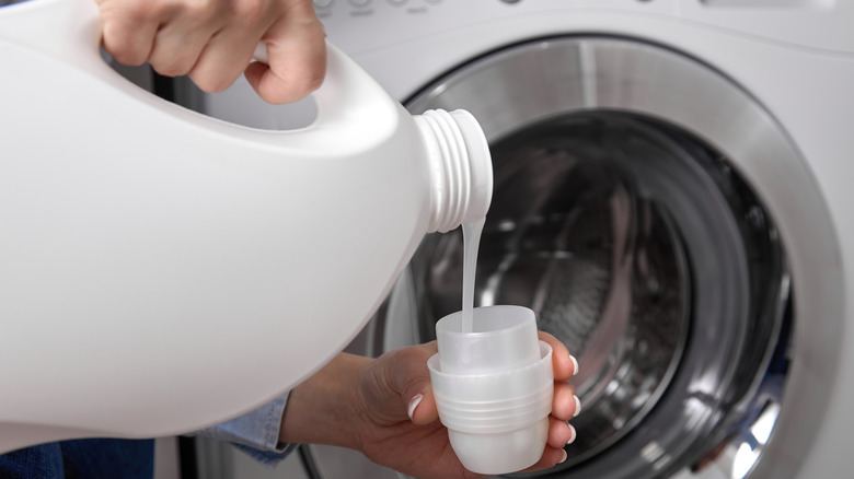 hands pouring laundry detergent