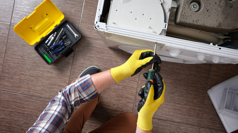 hands disassembling washer to repair