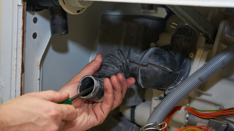 hands unclogging washer drain hose