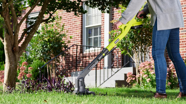 A person trimming their lawn with Ryobi's 18V One+ 10-inch Cordless Battery String Trimmer/Edger
