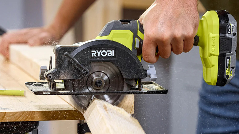 A person sawing lumber with Ryobi's 18V One+ Cordless 4-½-inch Circular Saw