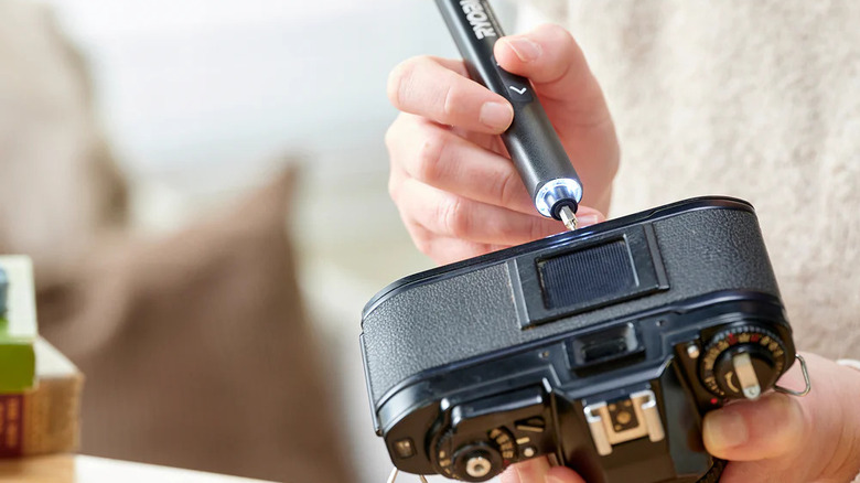 A person fixing a camera with Ryobi's MICROTECH Electric Precision Screwdriver