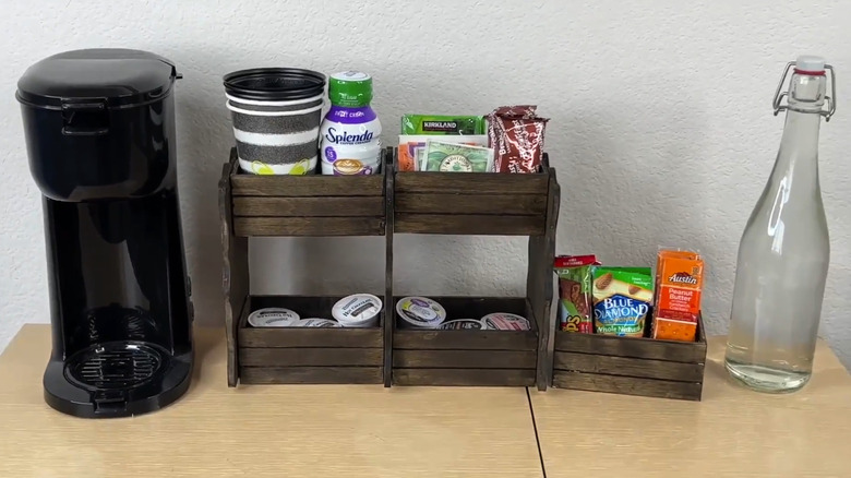 DIY coffee bar organizer with pods, tea, snacks, creamer, and cups near a single-cup coffee maker