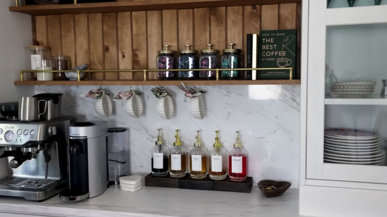 Coffee bar in a modern kitchen with an espresso machine and coffee syrups on dark wood blocks