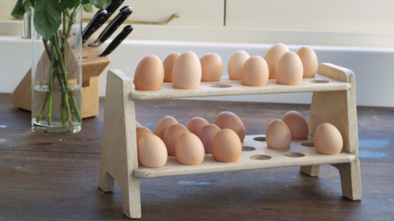 Eggs resting on a tiered wooden egg tray on a counter in a kitchen