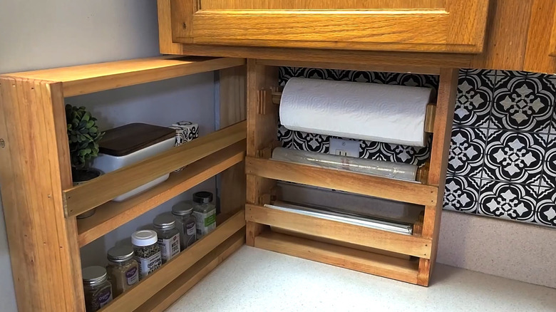 Wood shelf on a counter with paper towel, cling wrap, and tin foil installed on dowels