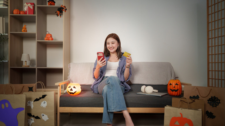 A happy woman shopping online with fall decor around her