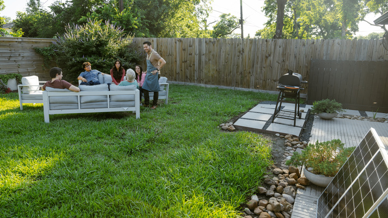 Family and friends gathered in the backyard with a grill on the side
