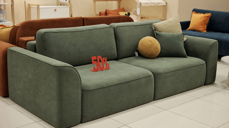 A muted olive green sofa on discount in a store