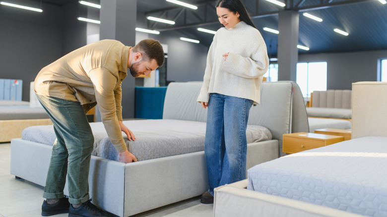 A young couple is looking at mattresses in a store