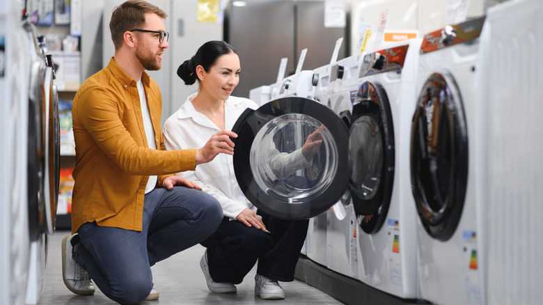 A happily shocked couple looking at washing machines in a store