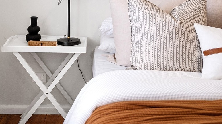 white luggage rack bedside table with lamp and decor on top