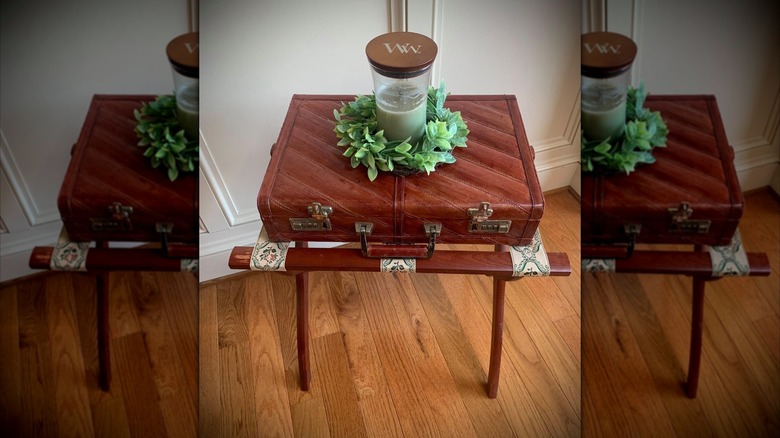 decorative luggage rack with suitcase and candle on top