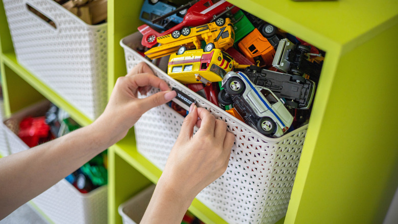 Hand placing label on storage shelf filled with toy bins
