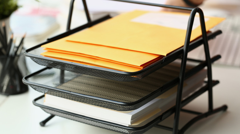 Papers on a tiered metal desk organizer shelf
